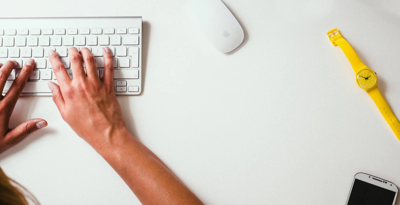 Mains sur un clavier d’ordinateur, sur un bureau blanc